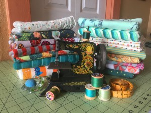 A picture of sewing tools, including a sewing machine, thread, a measuring tape, and fabric.